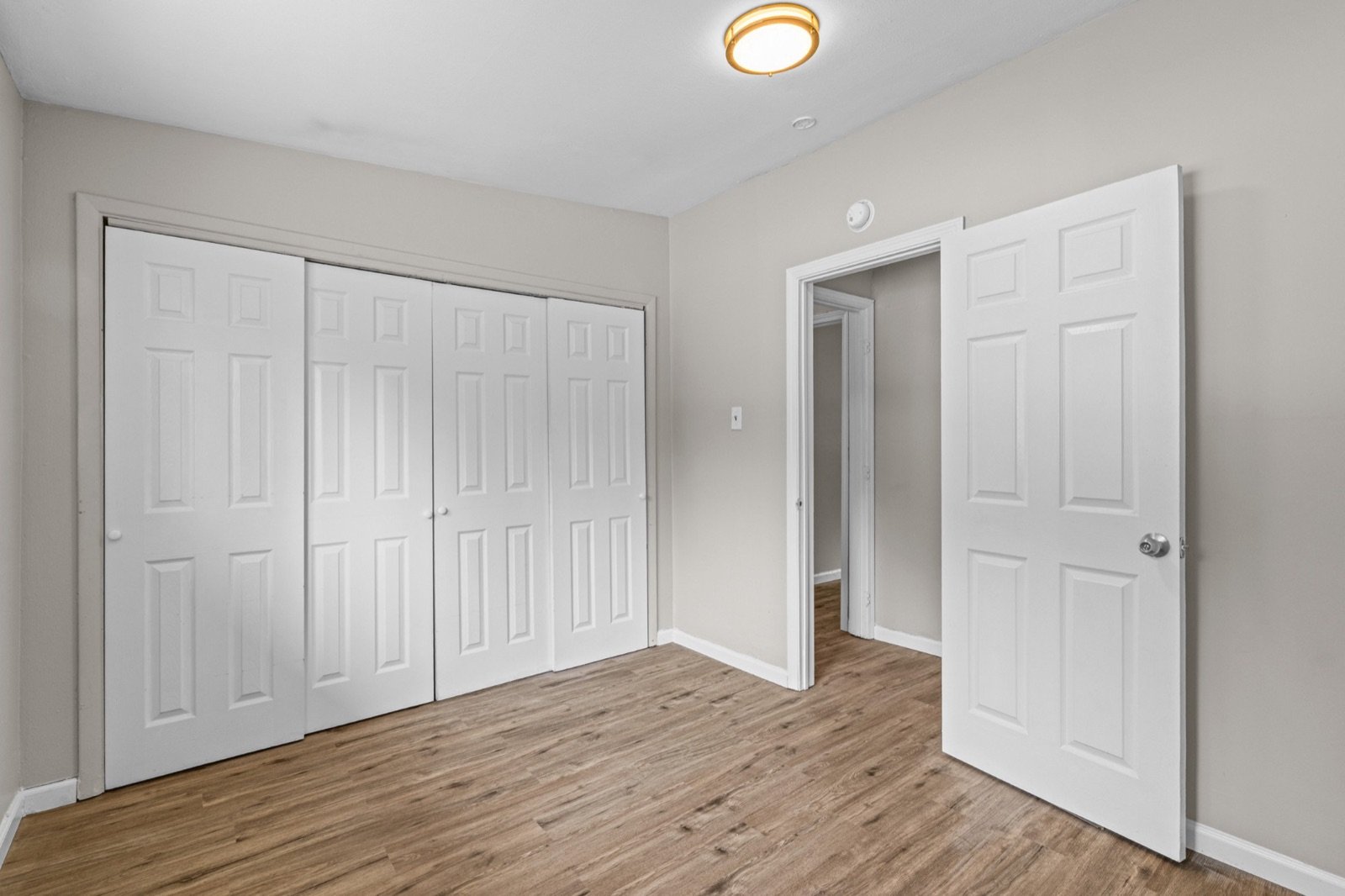 Bedroom with white six-panel closet doors and wood-look floors in the 2 bed, 1 bath St. Louis listing