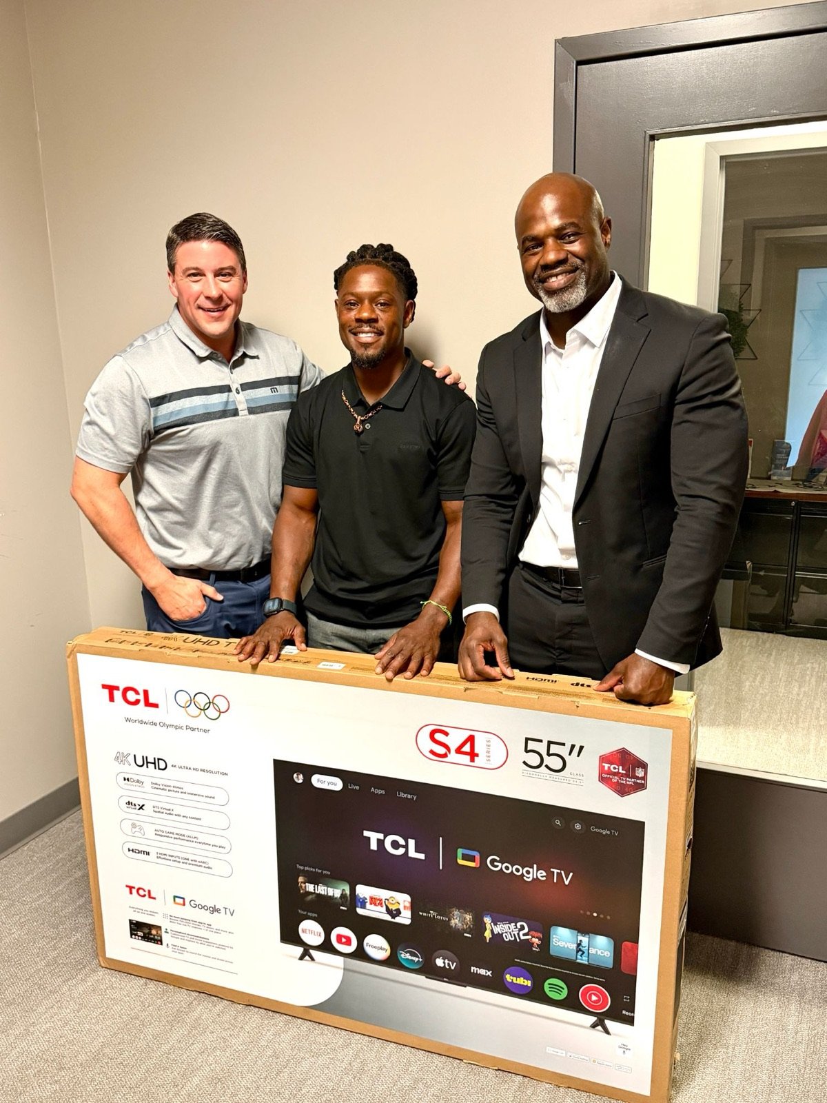 John Lewis with Tion and Andy standing behind a new television in its box