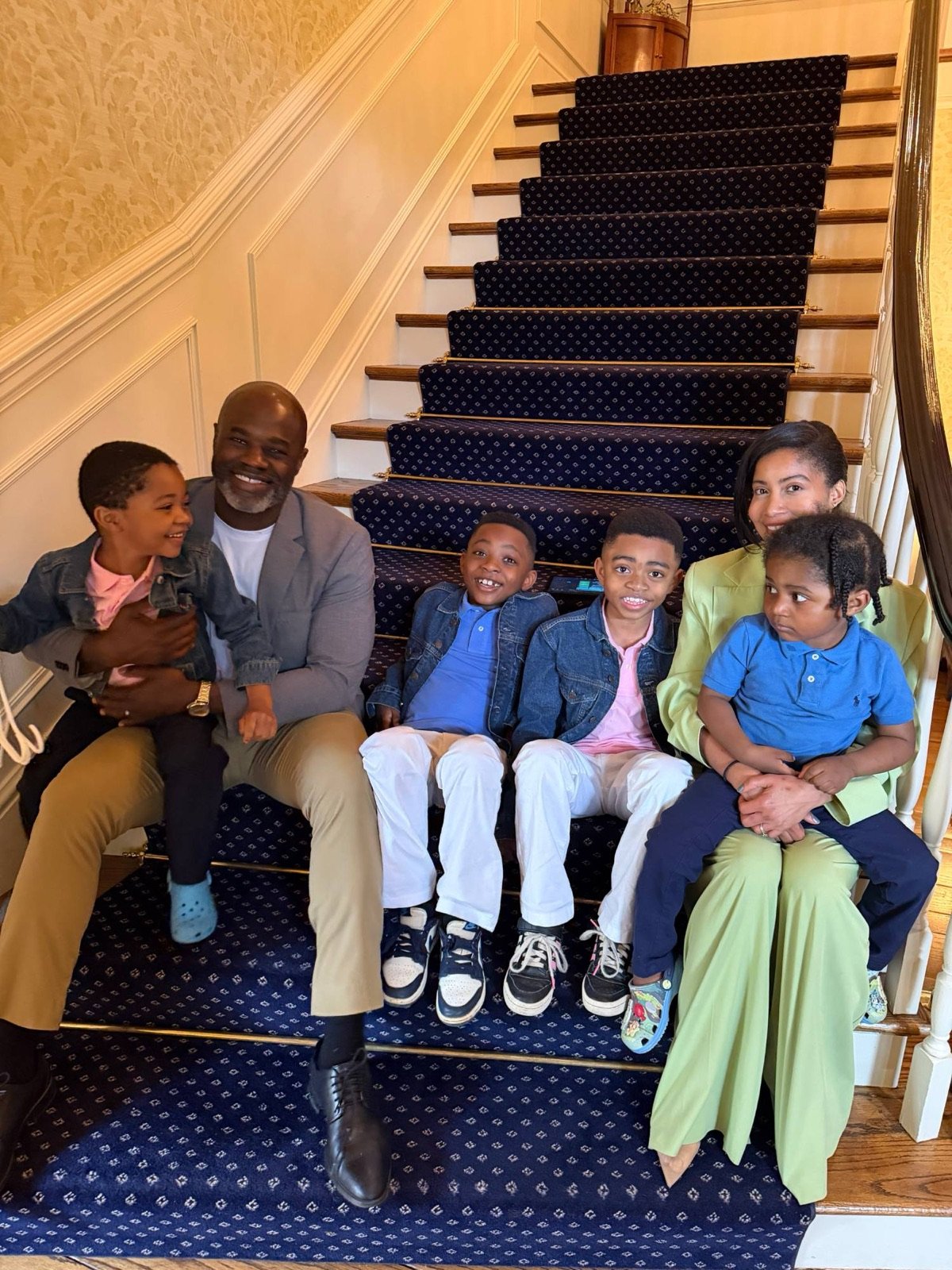 John Lewis with his wife and their four children sitting on a staircase at home