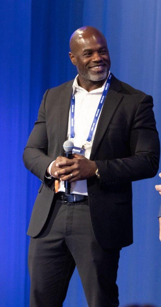 John Lewis smiling on stage, microphone in hand